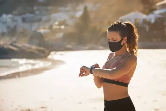 girl in mask using smartwatch in her workout